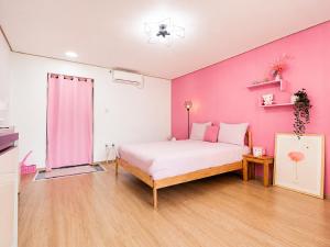 a bedroom with a pink wall and a bed at 오후여섯시펜션 in Jeju