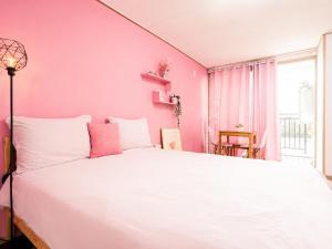 a pink bedroom with a white bed and a window at 오후여섯시펜션 in Jeju