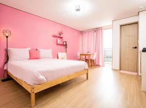 a bedroom with pink walls and a large bed at 오후여섯시펜션 in Jeju