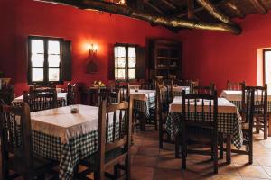 a restaurant with red walls and tables and chairs at Hotel Rural El Conceyu in Cabanella