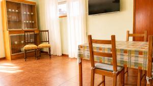 a dining room with a table and chairs and a television at Pôr do Sol in Vila Nova de Gaia