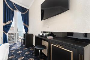 a hotel room with a desk with a flat screen tv at Arcadia Sea Breeze in Odesa