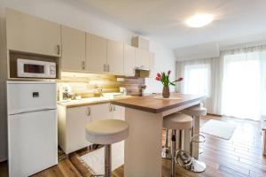 a kitchen with white cabinets and a counter with stools at Aqualiget-Apartmanház in Szeged