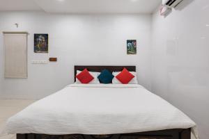 a bedroom with a bed with red and blue pillows at Sapthami Luxury Rooms in Guntūr