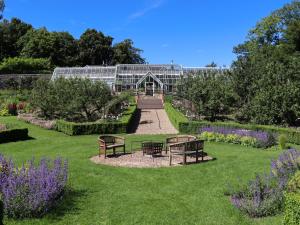 a glass house with benches in the middle of a garden at Heather Cottage - Uk52177 in Leven