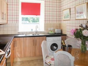 a kitchen with a sink and a washing machine at Heather Cottage - Uk52177 in Leven
