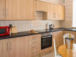 a kitchen with wooden cabinets and a red microwave at Heather Cottage - Uk52177 in Leven +12 photos