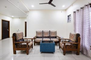 a room with two chairs and a bed in it at Sapthami Luxury Rooms in Guntūr