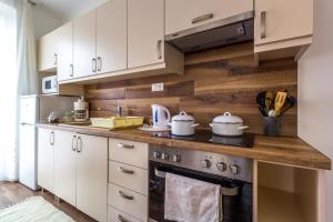 a kitchen with white cabinets and a stove with pots and pans at Aqualiget-Apartmanház E-Car plug-in point Szeged in Szeged +55 photos