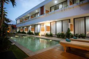 a hotel with a swimming pool in front of a building at JeKa Escotel & Loft in Seminyak