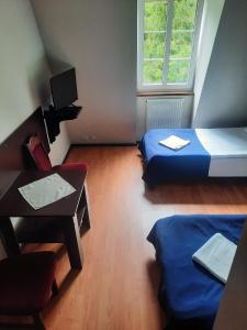 a room with two beds and a desk and a window at Dworek kwatery pracownicze in Kętrzyn +13 photos