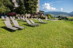 Eine Reihe von Gartenstühlen stand im Gras. in der Unterkunft Linta Hotel Wellness & Spa in Asiago + 39 Fotos