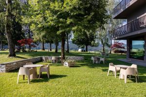 Eine Gruppe von Tischen und Stühlen im Gras in der Nähe eines Gebäudes in der Unterkunft Linta Hotel Wellness & Spa in Asiago