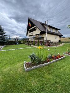 a building with a flower garden in front of it at Casa Sofia Dorna Candrenilor in Dorna Cîndrenilor