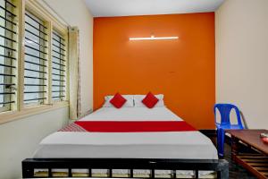 a bedroom with a bed with an orange wall at SPOT ON Ganesh in Kaglipur