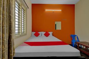 a bedroom with a bed with an orange wall at SPOT ON Ganesh in Kaglipur +21 photos