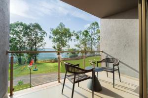 a balcony with two chairs and a table and a view at Ayati Resort & Spa in Panchgani