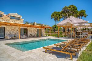 a house with a swimming pool with chairs and umbrellas at Alestone Villa by the sea in Vasilikos