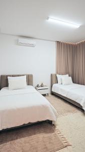 two beds in a room with white walls at chez moi sfax ville in Sfax