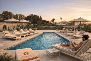 a man reading a book next to a swimming pool at Villa ArboreA in Squinzano