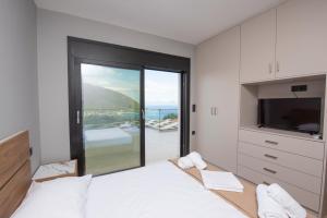 a bedroom with a bed and a tv and a balcony at Aifantis Villa 2 in Póndi +71 photos