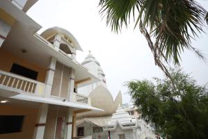 a building with a balcony and a palm tree at Shanti Sewa Dham in Chhatikara