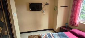 a bedroom with a bed and a tv on the wall at Yamuna rooms and dormitory in Ooty