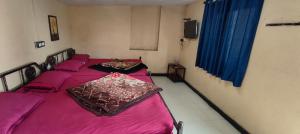 two twin beds in a room with pink sheets at Yamuna rooms and dormitory in Ooty