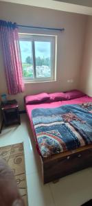 a small bedroom with a bed with a window at Yamuna rooms and dormitory in Ooty