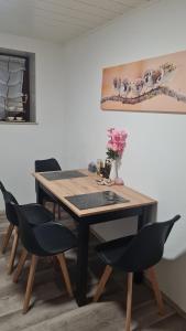a dining room table with chairs and a vase with flowers at Moderne, ruhige Ferienwohnung! in Geistingen +8 photos