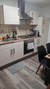 a kitchen with white cabinets and a black stove top oven at Moderne, ruhige Ferienwohnung! in Geistingen