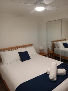 a bedroom with a large white bed with blue and white pillows at Oceanfront Ground Floor Apartment - Dwell 3 in Bargara in Bargara
