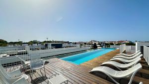 a deck with chairs and a swimming pool on a building at Prime - Shared Pool - 6 Guests - Albufeira in Albufeira