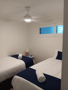 a bedroom with two beds and a ceiling fan at Oceanfront Ground Floor Apartment - Dwell 3 in Bargara in Bargara