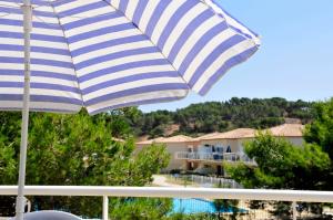 a blue and white umbrella on a balcony with a pool at Résidence Goélia Les Jardins De Phoebus in Gruissan