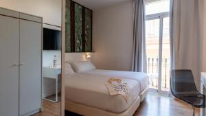 a hotel room with a bed and a window at chic&basic Tallers Hostal in Barcelona