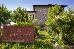 a sign in front of a stone house with trees at Massoni Wine Relais in Peschiera del Garda