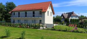 a white house with a red roof and a fence at Willa Róż in Rusinowo