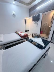 two beds in a room with a shower at Hotel Broadway Colaba in Mumbai +23 photos