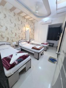 a hospital room with three beds and a tv at Hotel Broadway Colaba in Mumbai