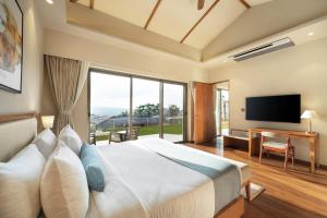 a bedroom with a large bed and a large window at Ayati Resort & Spa in Panchgani