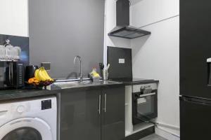 a kitchen with a sink and a washing machine at Studio - Sleeps 2 - 5 Min to Trains - Parking in Thornton Heath
