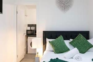 a bedroom with a bed with green and white pillows at Studio - Sleeps 2 - 5 Min to Trains - Parking in Thornton Heath