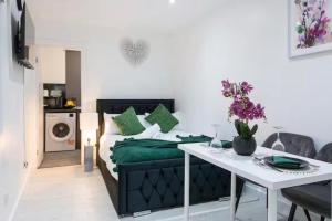 a bedroom with a bed with green pillows and a table at Studio - Sleeps 2 - 5 Min to Trains - Parking in Thornton Heath