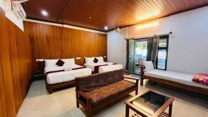 a room with two beds and a couch in it at Gavadana Resort Coorg in Madikeri