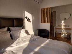 a bedroom with a large white bed and a chair at L'appartement de Sigrid in Pézenas