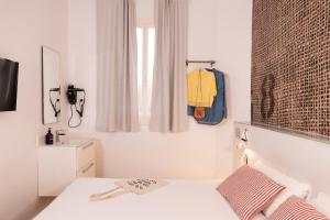 a white bedroom with a bed and a window at chic&basic Tallers Hostal in Barcelona