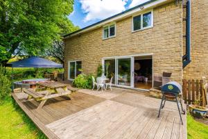 a wooden deck with a picnic table and a grill at Ascot House in Buxton