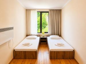 two beds in a room with a window at Eka's guest house in Mestia