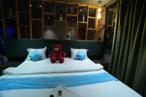 a red teddy bear sitting on top of a bed at Roots in Pune